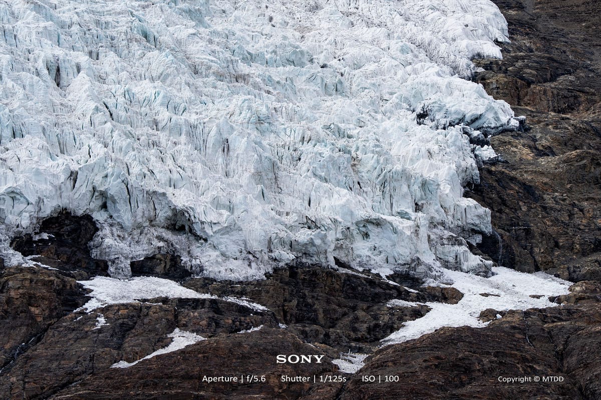 Massive glacier with jagged white ice formations cascading over dark rocky terrain