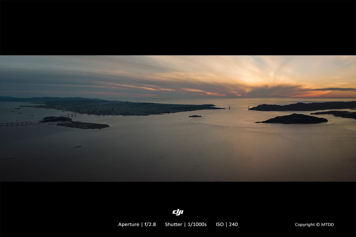 Panoramic sunset view of San Francisco Bay with Golden Gate Bridge silhouetted against dramatic orange sky and scattered islands