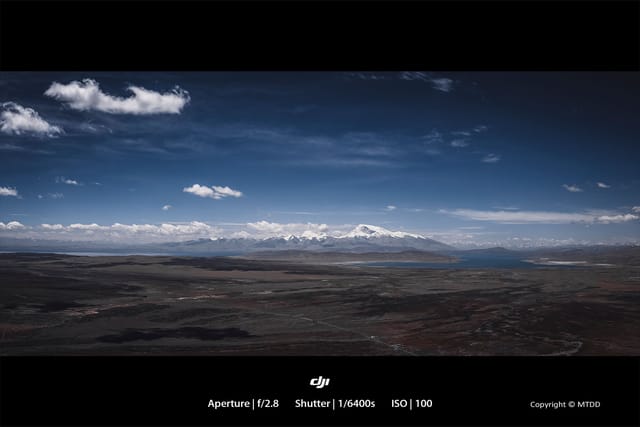 Aerial view of sacred Tibetan lakes Rakshastal and Manasarovar, surrounded by rugged mountain terrain under dramatic sky