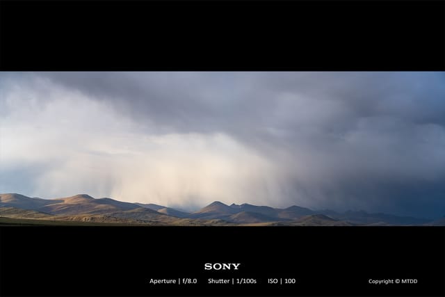 Storm clouds gathering over arid mountainous landscape with dramatic rainfall