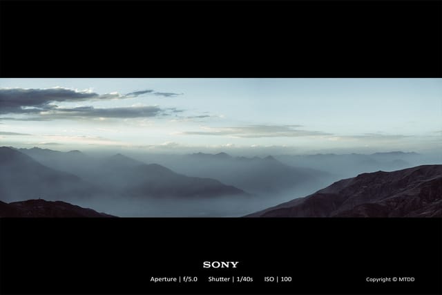 Misty mountain panorama with layered peaks shrouded in dawn's soft light